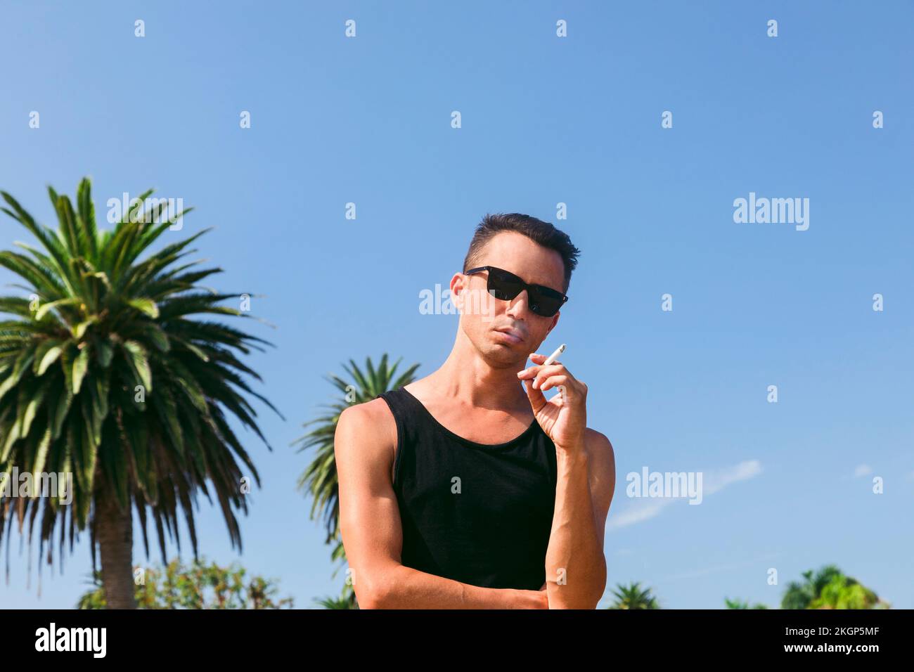 Ein Mann mit Zigarette steht vor dem blauen Himmel Stockfoto