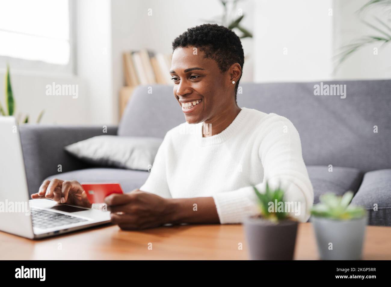 Glückliche Frau mit Kreditkarte und Laptop zu Hause Stockfoto