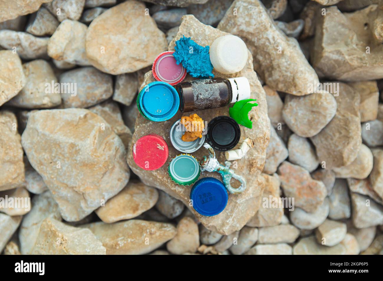 Flaschenkappen und Müll auf Stein am Strand Stockfoto