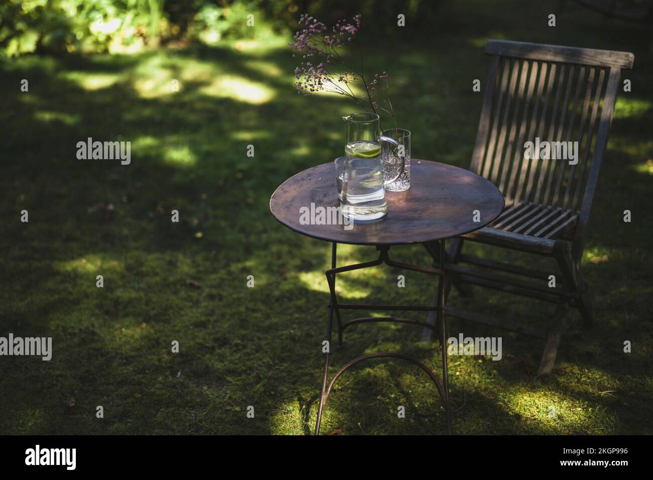 Tisch und Stuhl mit Wasserkanne im Garten Stockfoto