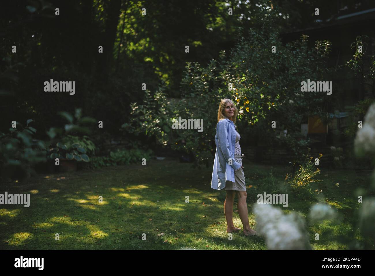 Frau in legerer Kleidung, die im Garten auf Gras steht Stockfoto