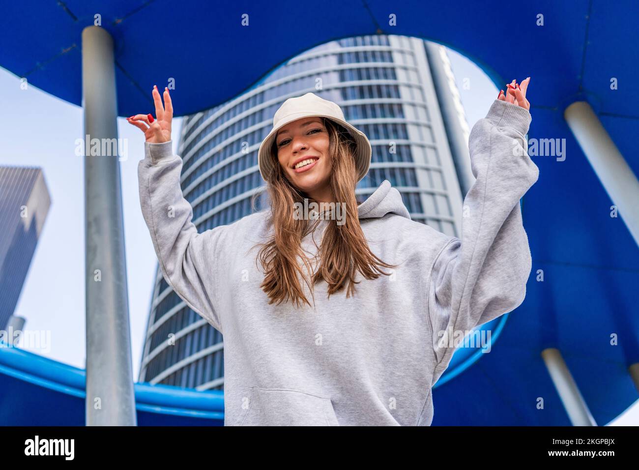 Glückliche Frau, die mit erhobenen Armen vor dem Gebäude steht Stockfoto
