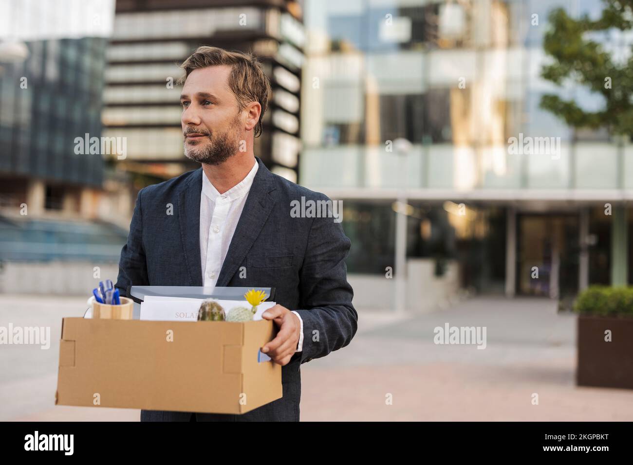 Geschäftsmann mit Pappkarton außerhalb des Bürogebäudes Stockfoto
