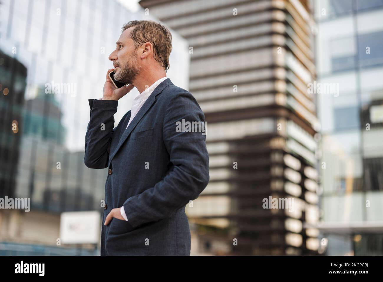 Geschäftsmann, der sich vor dem Gebäude über ein Smartphone unterhält Stockfoto