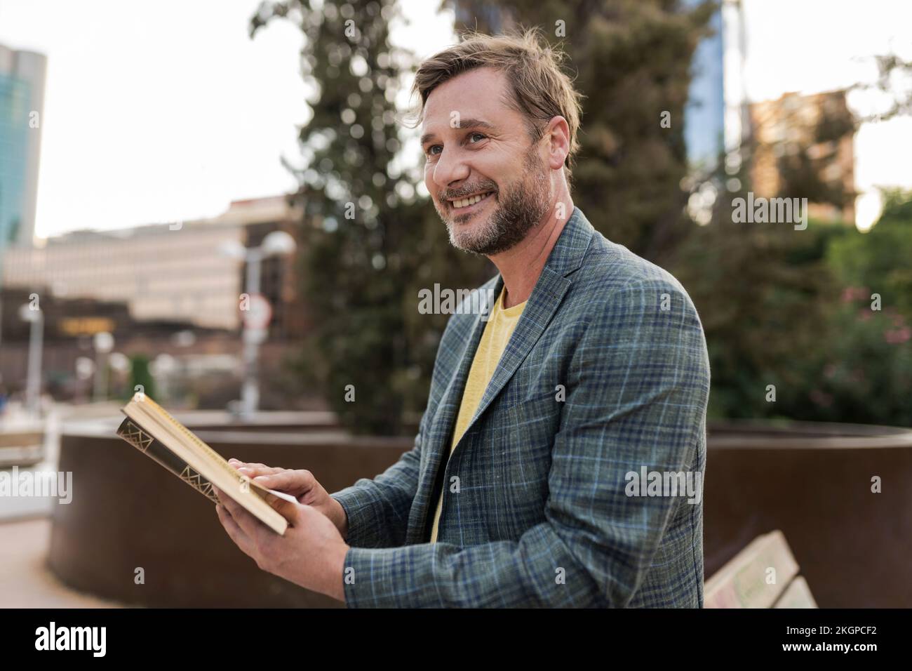 Glücklicher Mann mit Buch auf der Bank Stockfoto