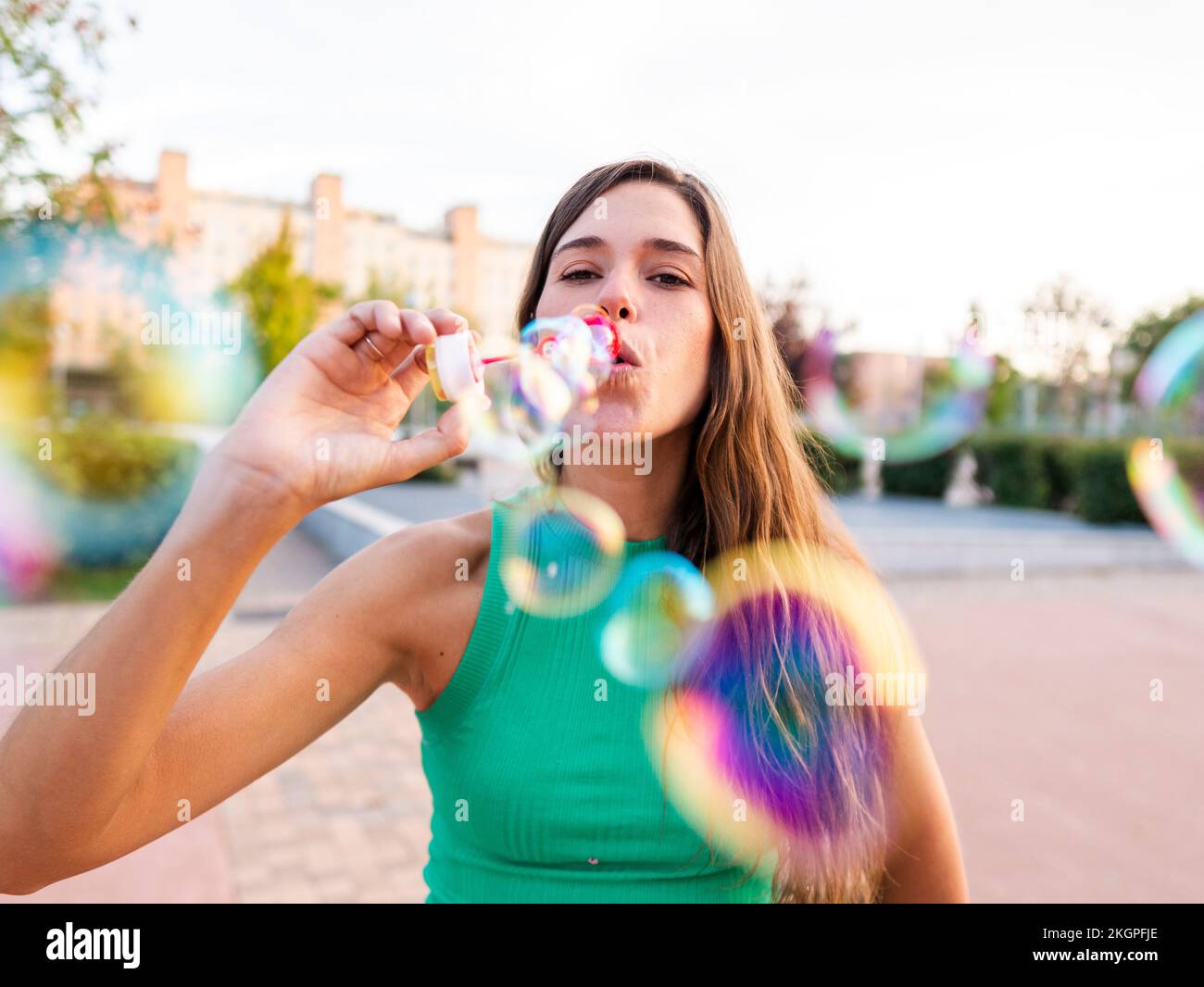 Eine Frau bläst bunte Blasen auf dem Fußweg Stockfoto