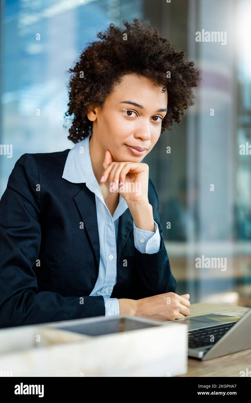 Geschäftsfrau mit der Hand am Kinn im Büro Stockfoto