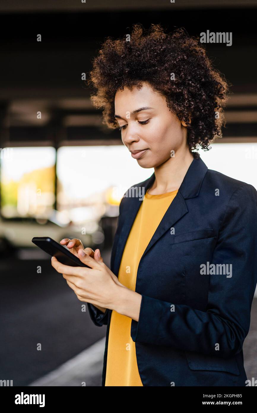 Geschäftsfrau, die einen Blazer trägt und ein Smartphone benutzt Stockfoto