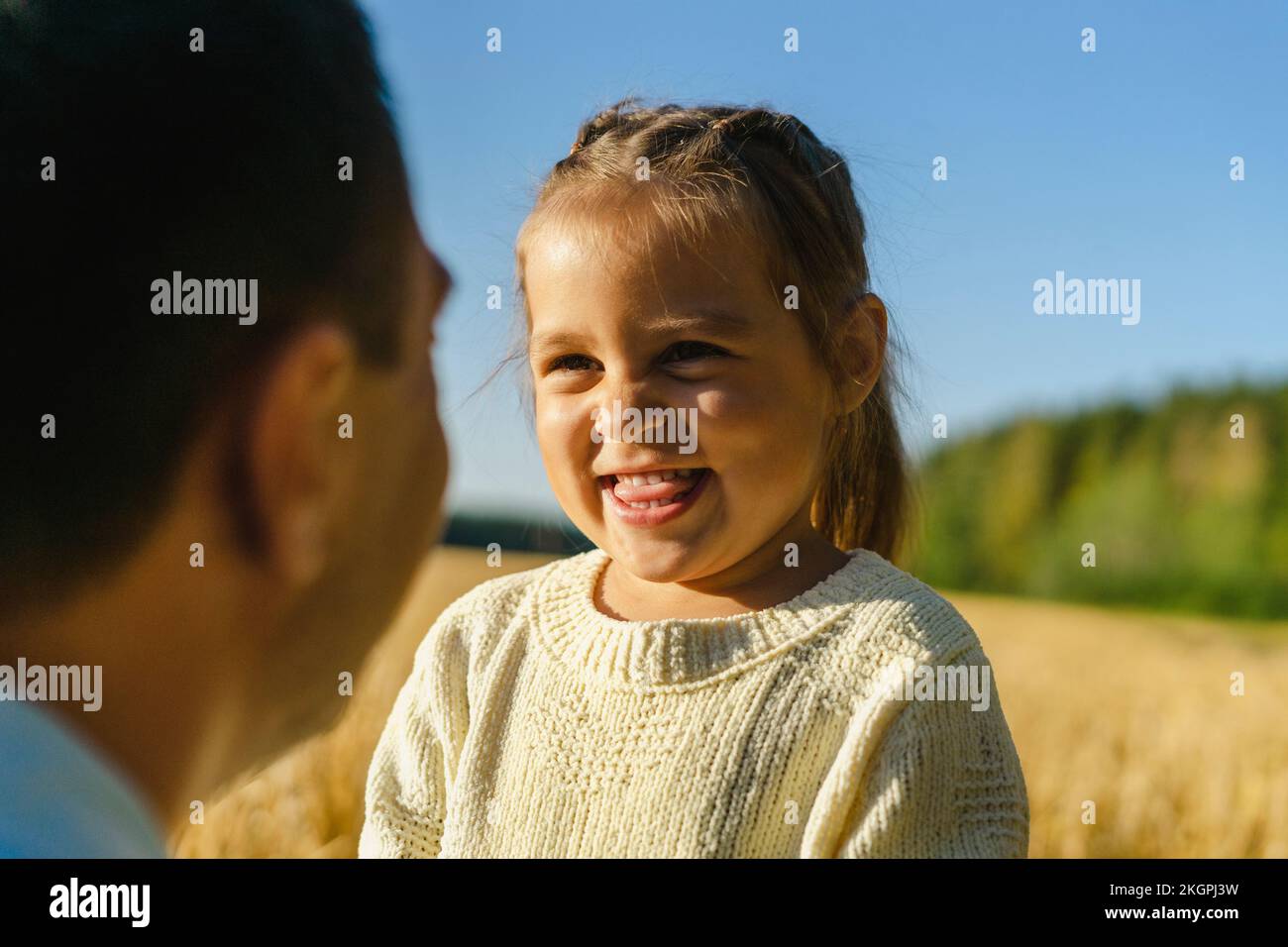 Glückliches süßes Mädchen mit Vater auf dem Feld an einem sonnigen Tag Stockfoto