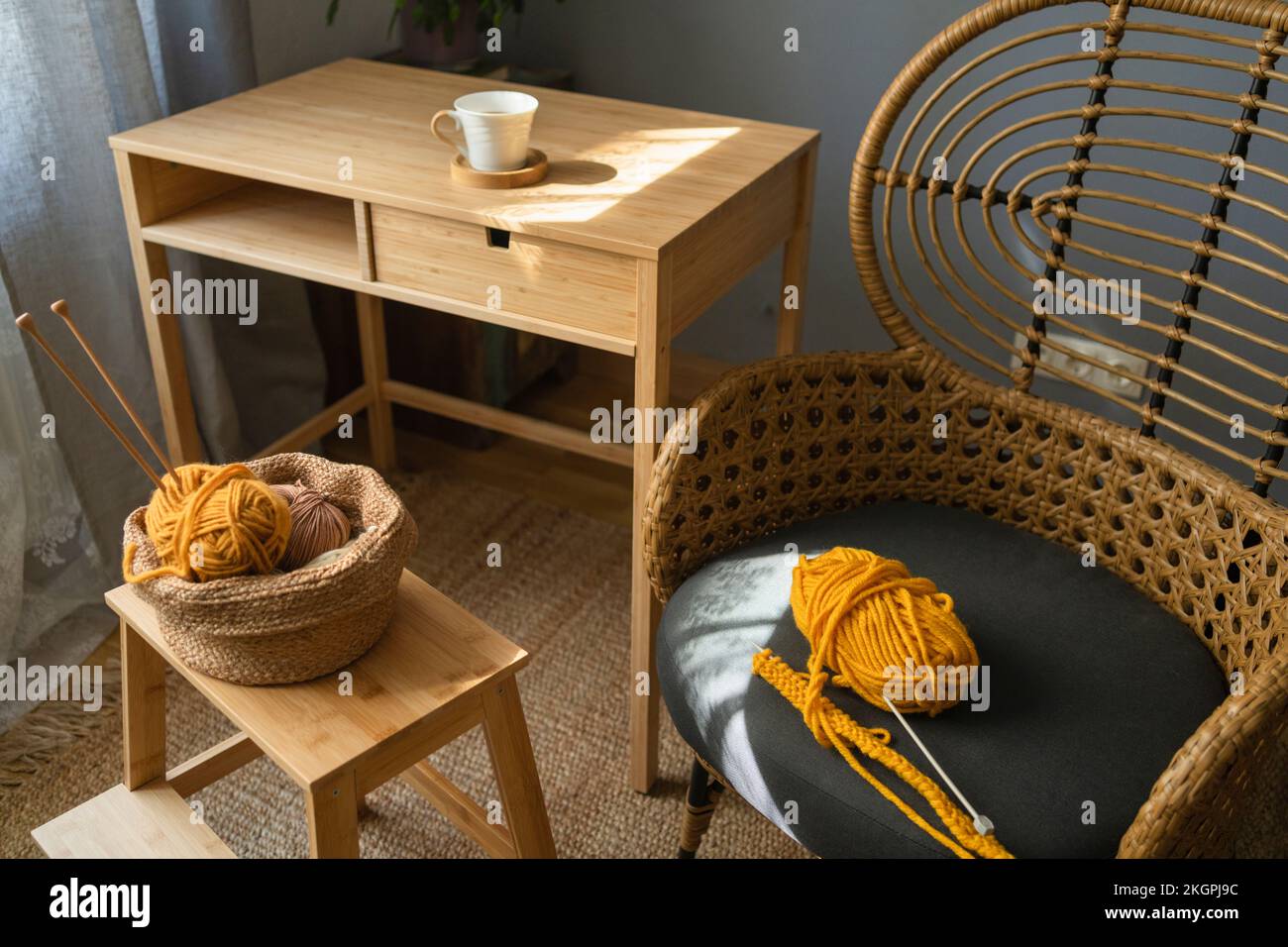 Wollknäuel im Korb und auf dem Stuhl zu Hause Stockfoto