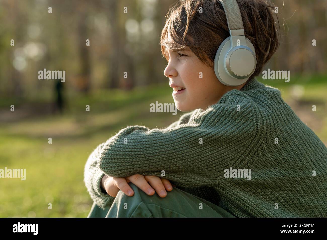 Junge, der im Park Musik über kabellose Technologie hört Stockfoto