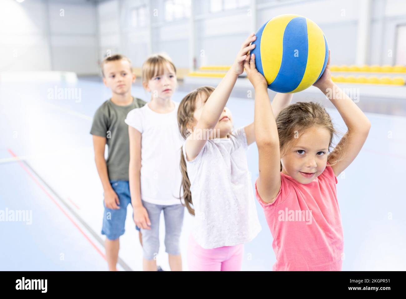 Mädchen, die den Ball an eine Freundin weitergibt, die sich am Schulsportplatz anstellt Stockfoto