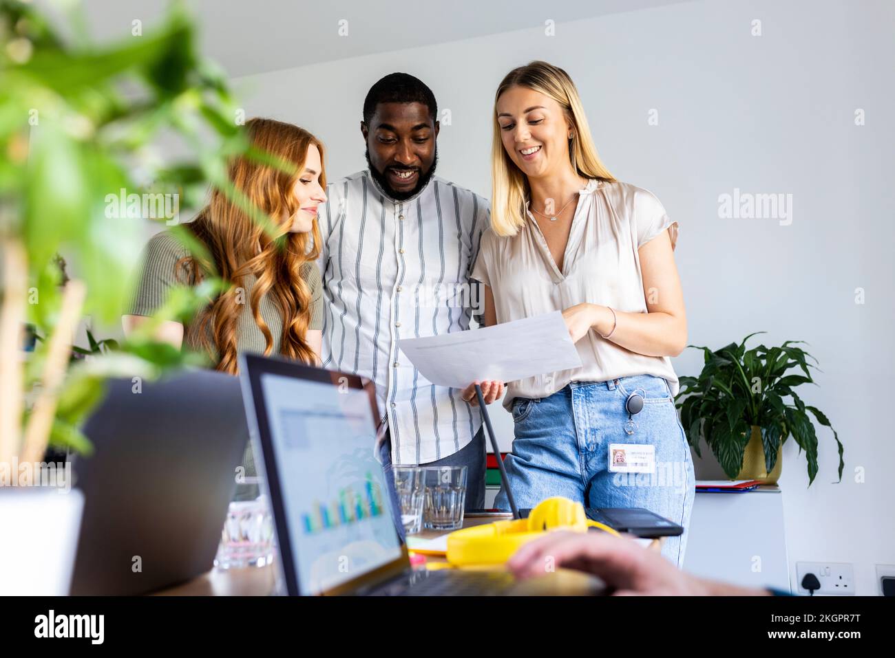 Lächelnde Geschäftskollegen, die in einer Bürobesprechung über ein Papierdokument sprechen Stockfoto