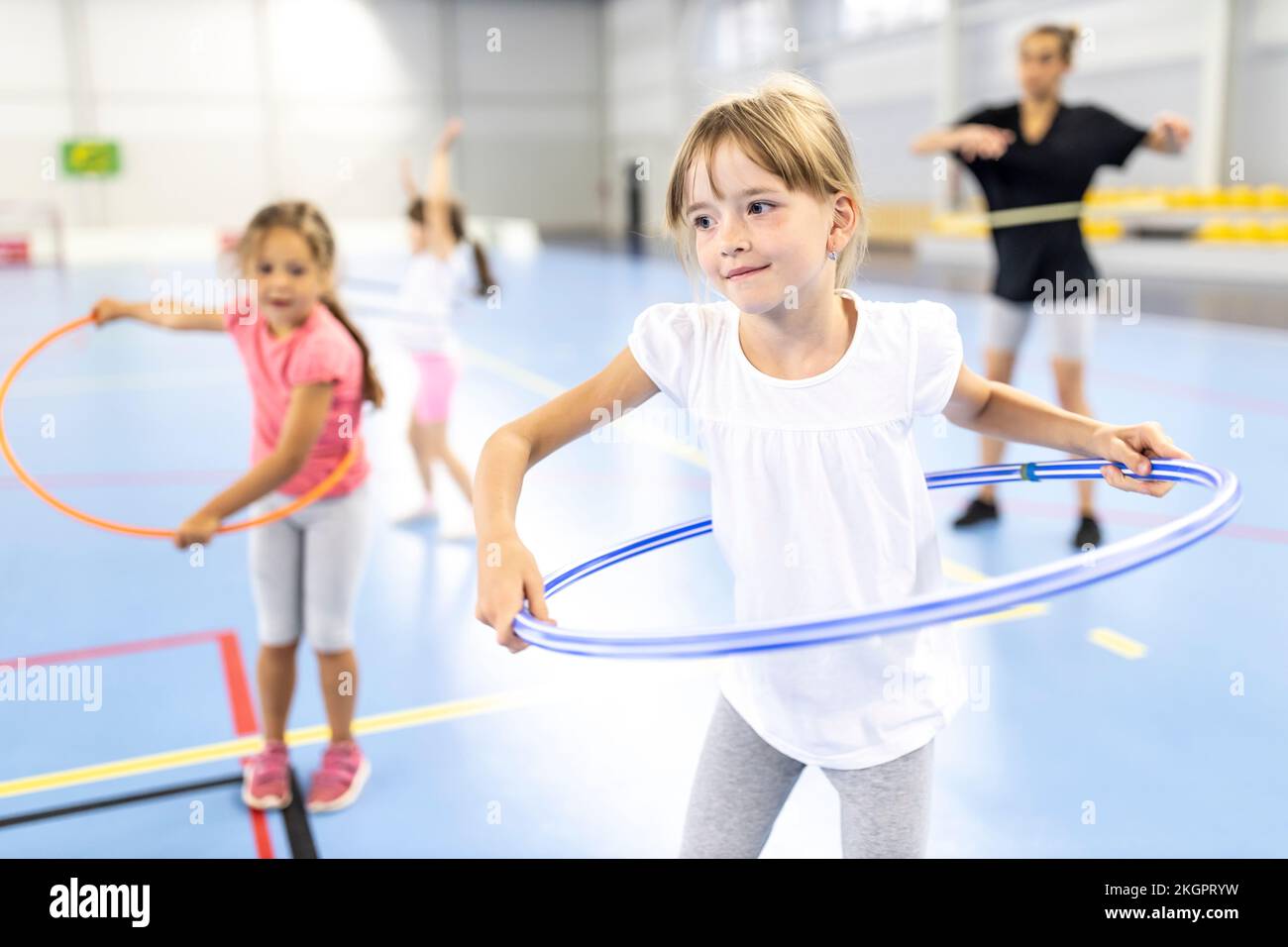 Ein Mädchen, das Hula-Hoop auf dem Schulsportplatz praktiziert Stockfoto