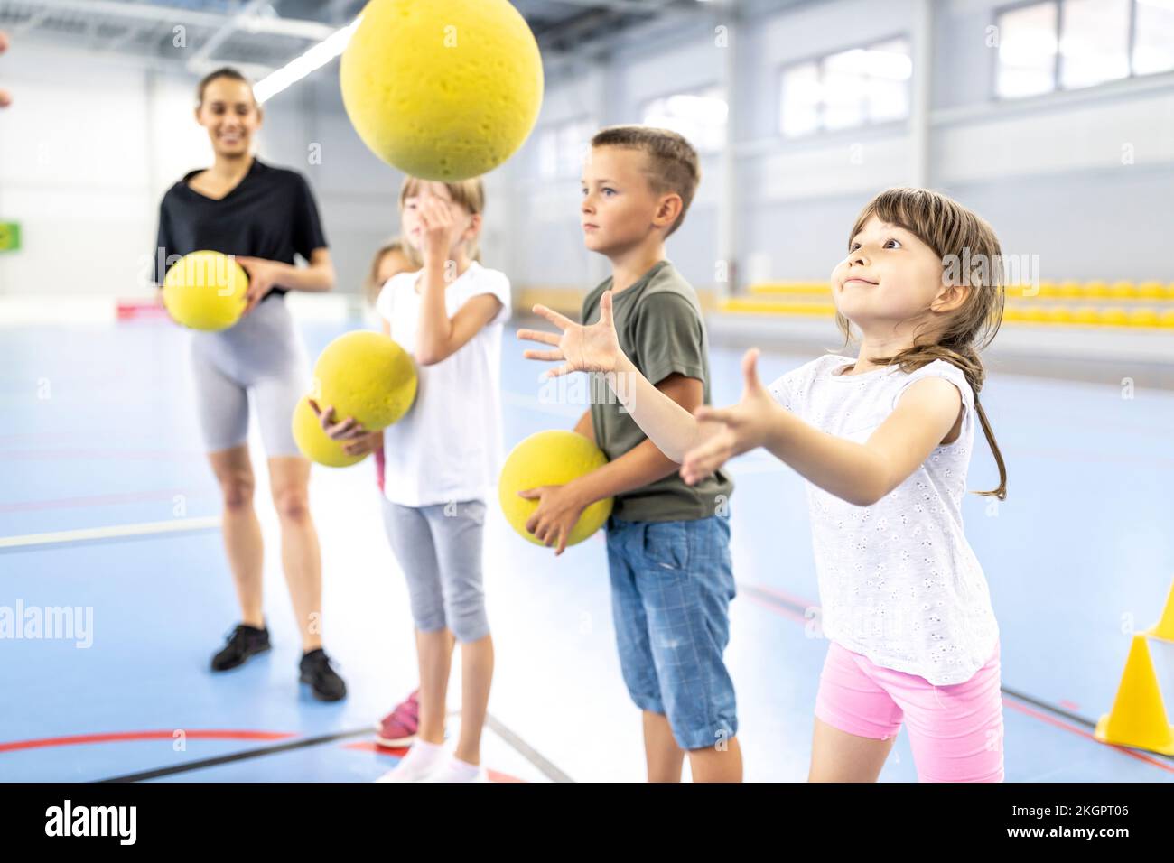 Grundschüler, die auf dem Schulsportplatz mit Ball spielen Stockfoto