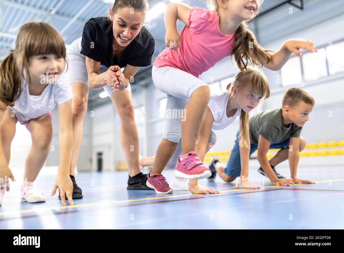 Ein Mädchen, das mit Freunden ein Rennen beginnt, von einem Lehrer, der im Hintergrund jubelt Stockfoto