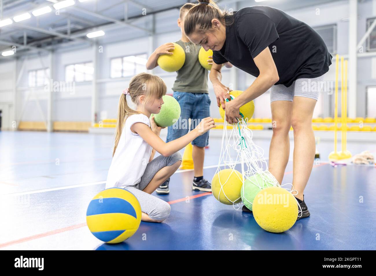 Lehrer und Schüler entfernen Bälle aus dem Netz am Schulsportplatz Stockfoto