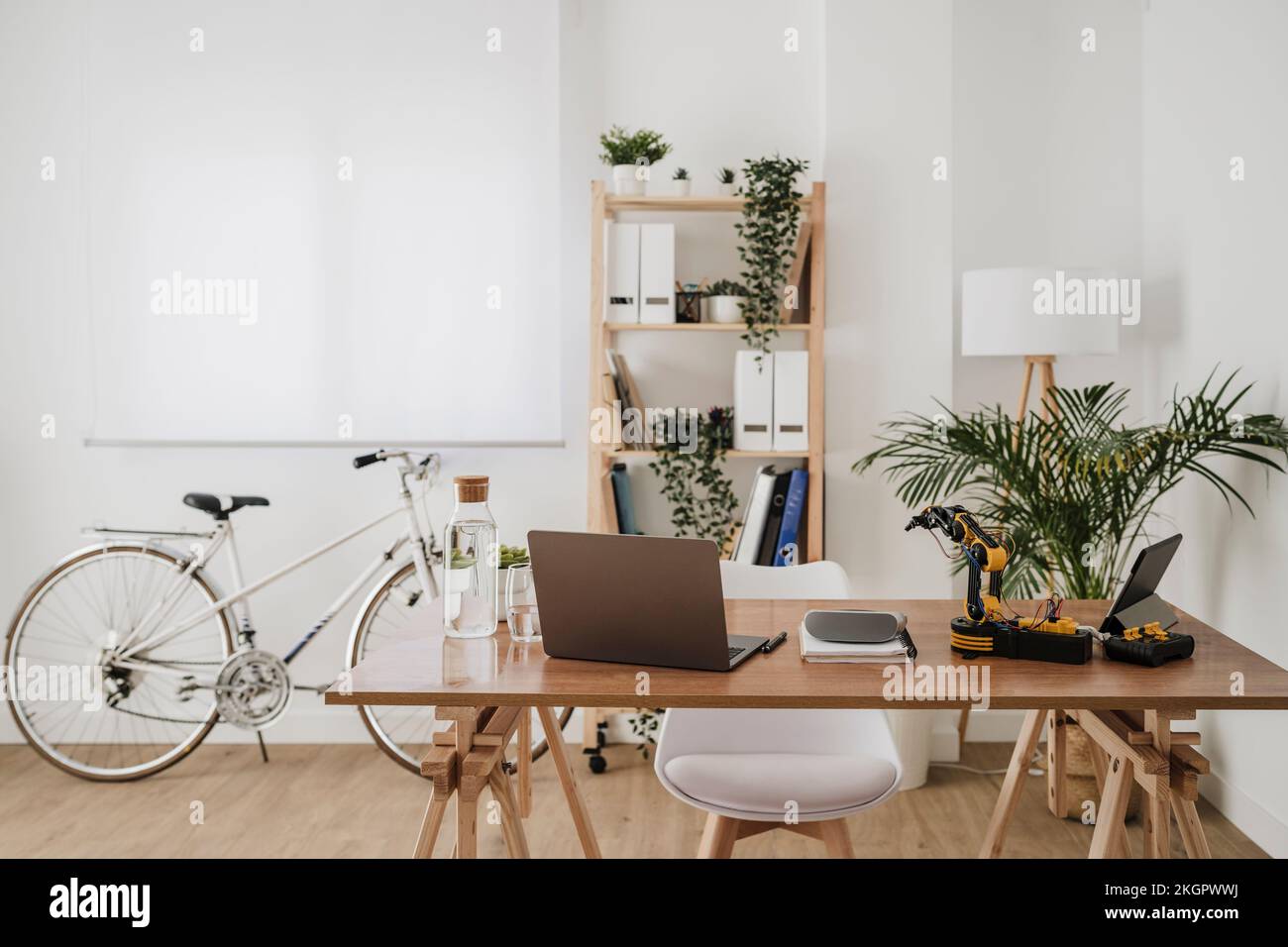 Moderne Technologien am Schreibtisch mit Fahrrad und Regal im Hintergrund im Büro Stockfoto