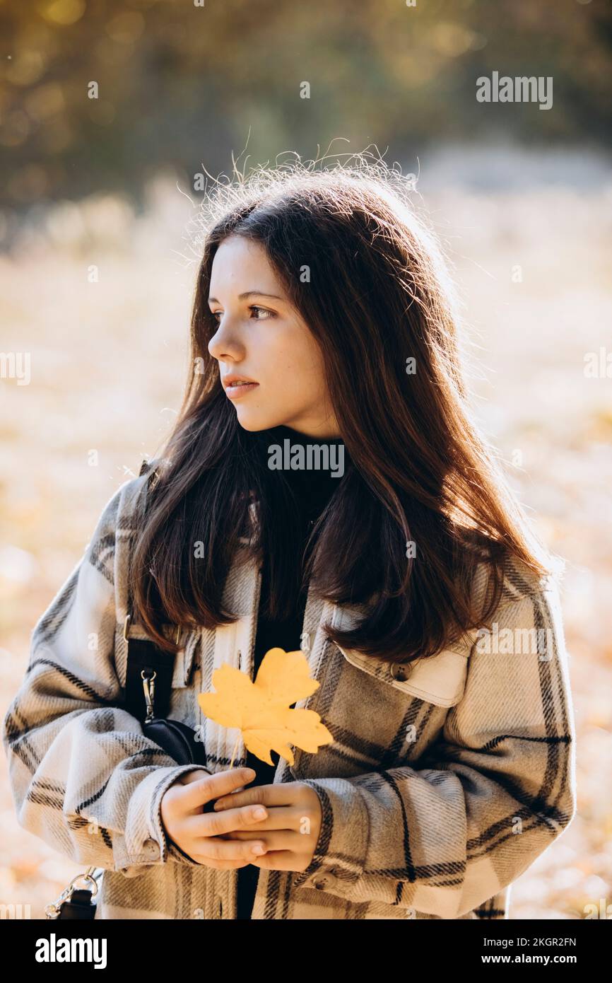 Rücksichtsvolles Mädchen, das Ahornblatt hält, steht an einem sonnigen Tag Stockfoto