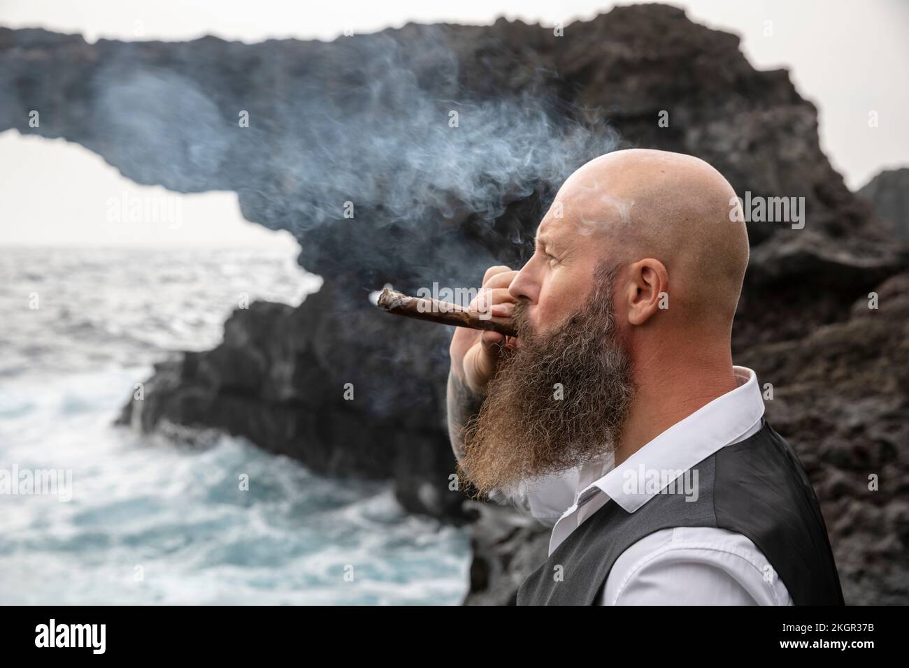 Reifer Mann, der vor dem Felsen Zigarre raucht Stockfoto