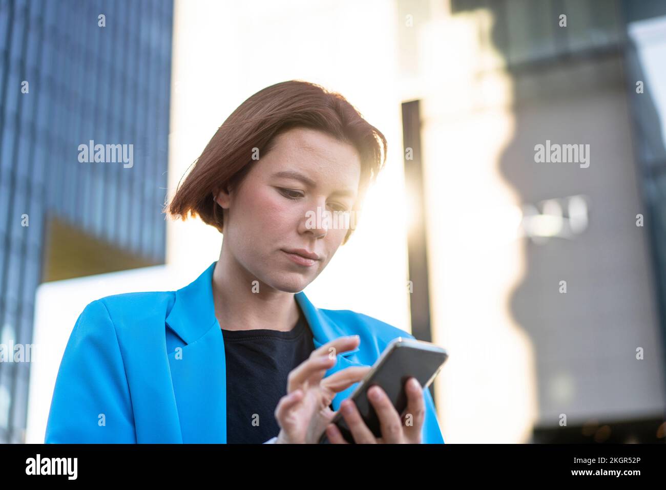 Geschäftsfrau mit kurzen Haaren, die ein Mobiltelefon benutzt Stockfoto