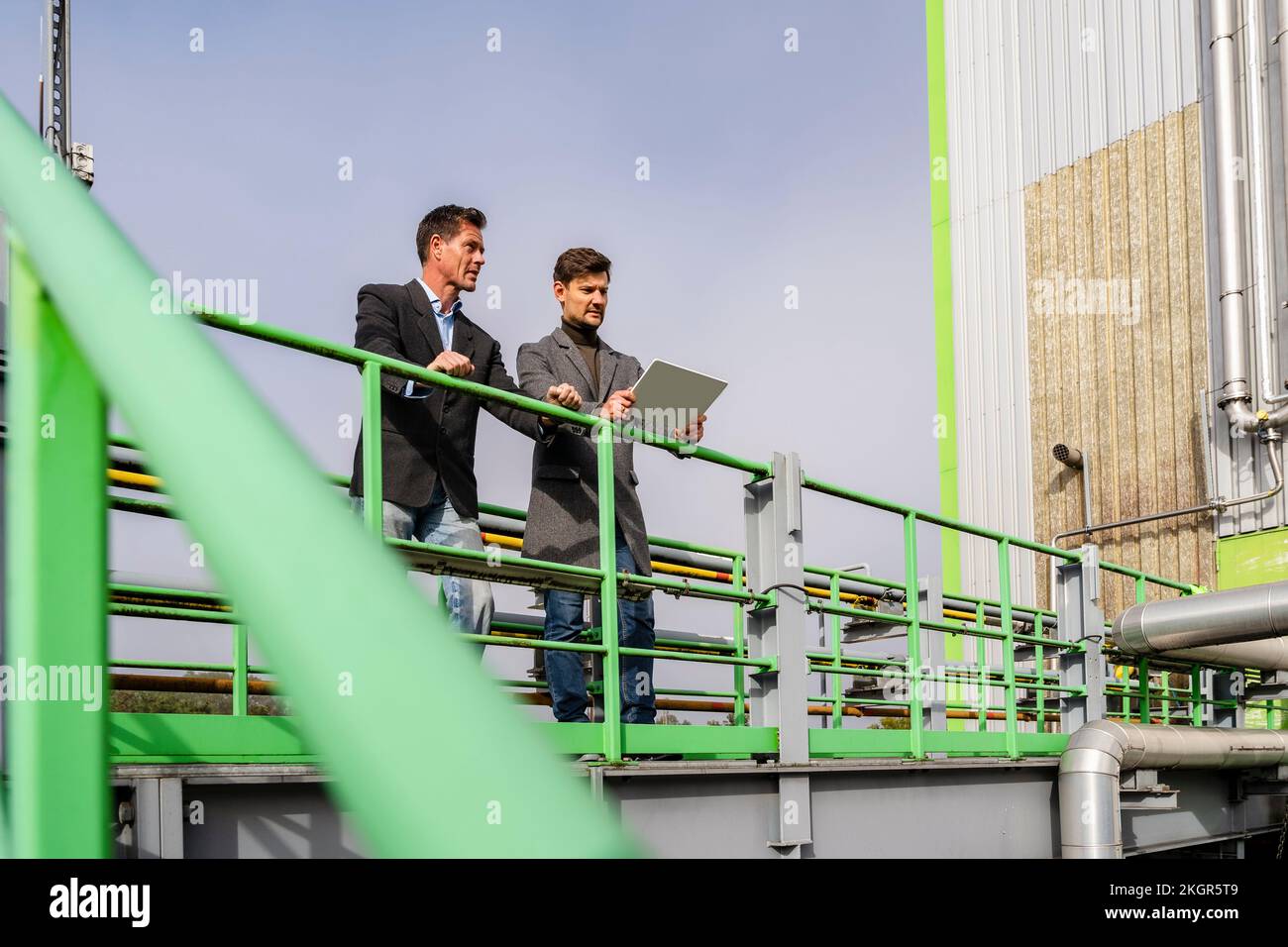 Ein Geschäftsmann mit einem Kollegen steht am Geländer in der Recyclingstation Stockfoto
