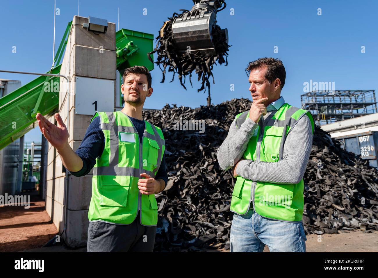 Ein Mann, der vor dem Bagger im Recycling-Center spricht Stockfoto