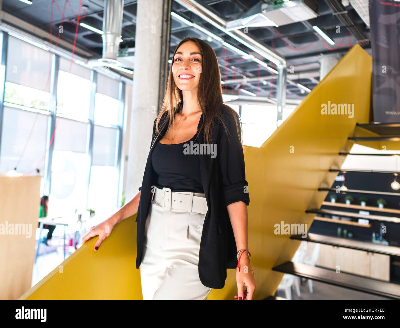 Lächelnde Geschäftsfrau, die von den Stufen im Büro herunterkommt Stockfoto