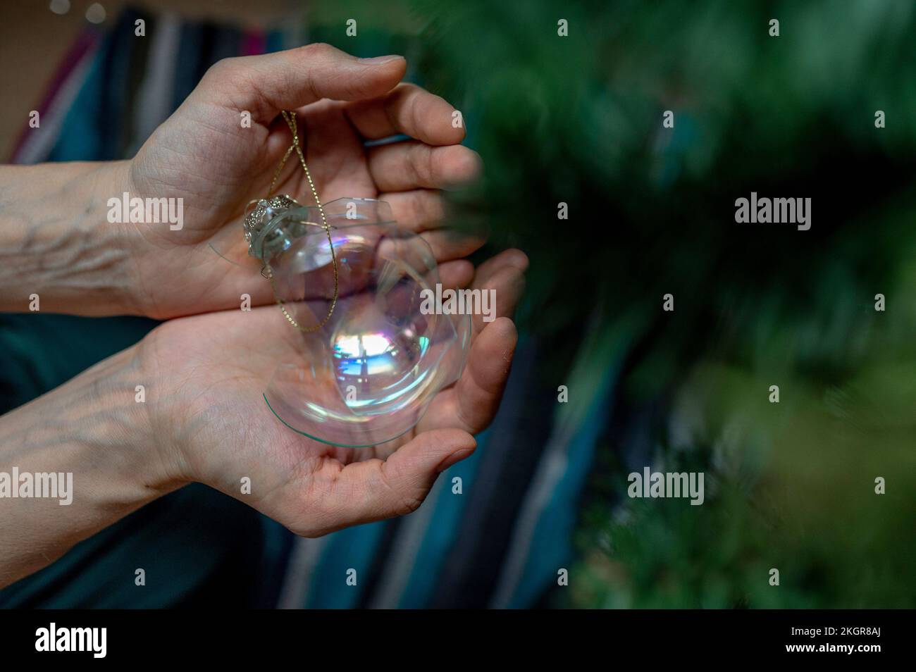 Hände einer Frau, die zu Hause ein kaputtes Weihnachtsspielzeug in der Hand hält Stockfoto