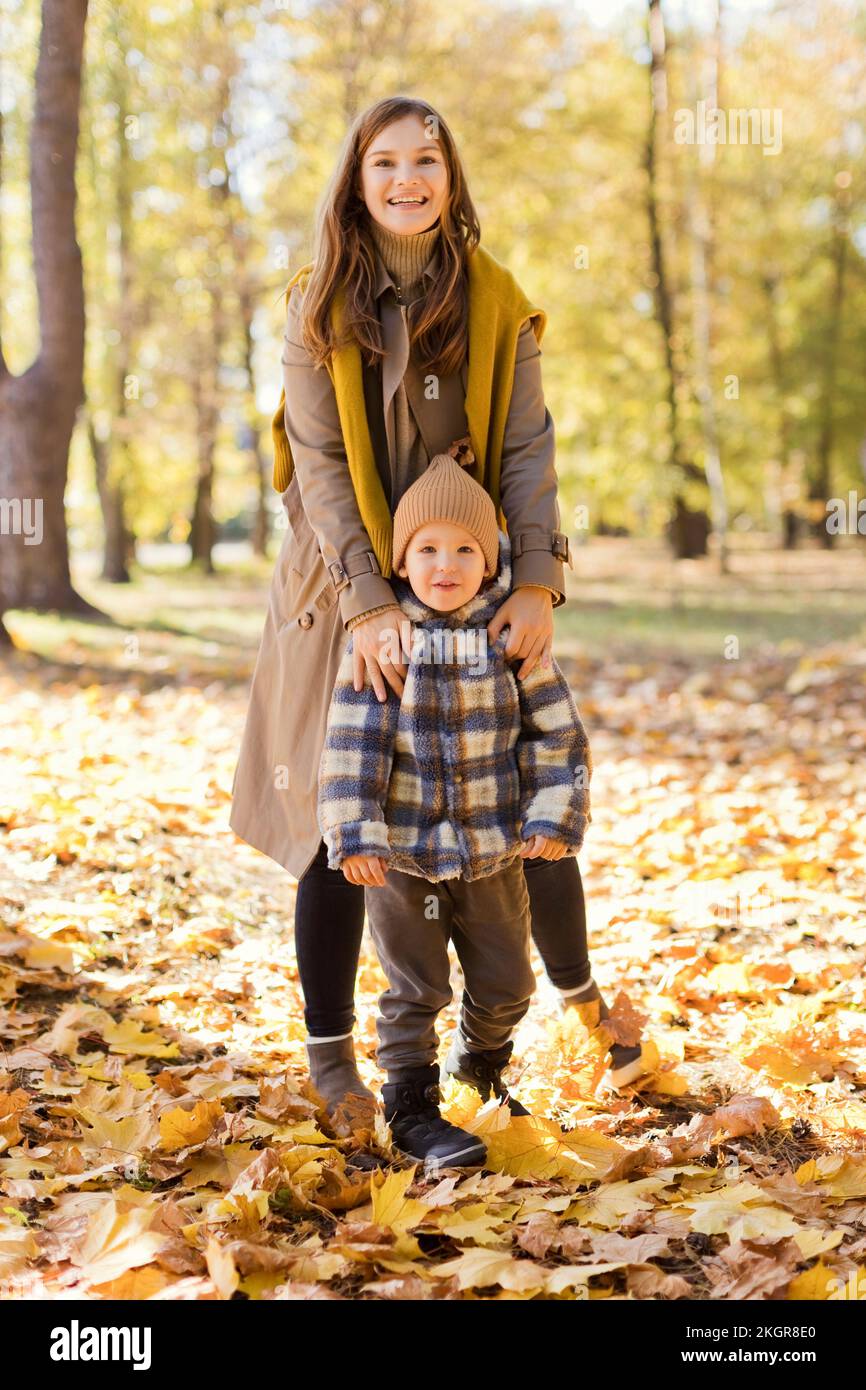 Glückliche Mutter und Sohn stehen auf Herbstblättern im Park Stockfoto