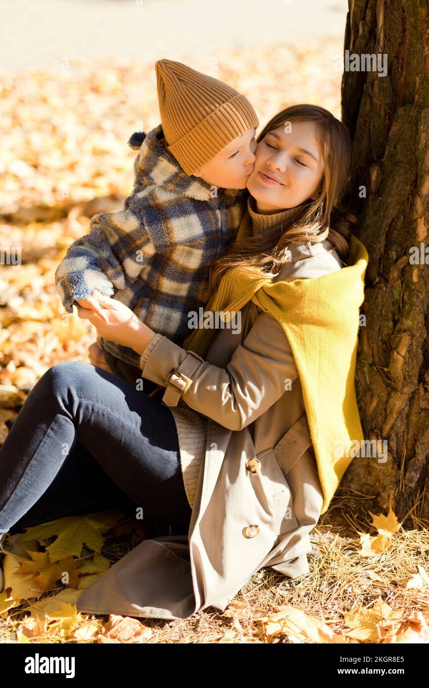 Sohn küsst Mutter lehnt sich im Park an den Baum Stockfoto