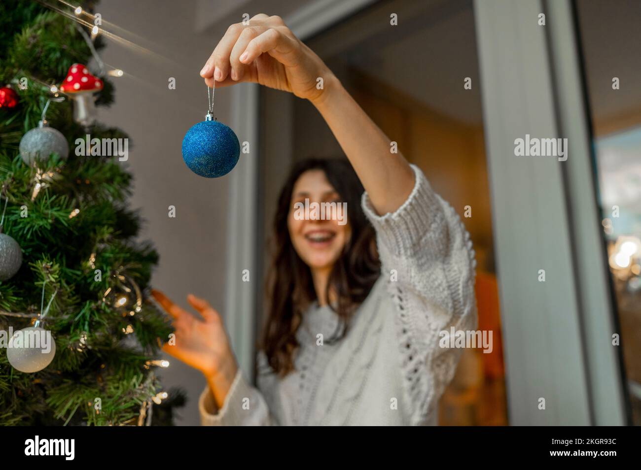 Frau mit Weihnachtsschmuck, um den Weihnachtsbaum zu schmücken Stockfoto