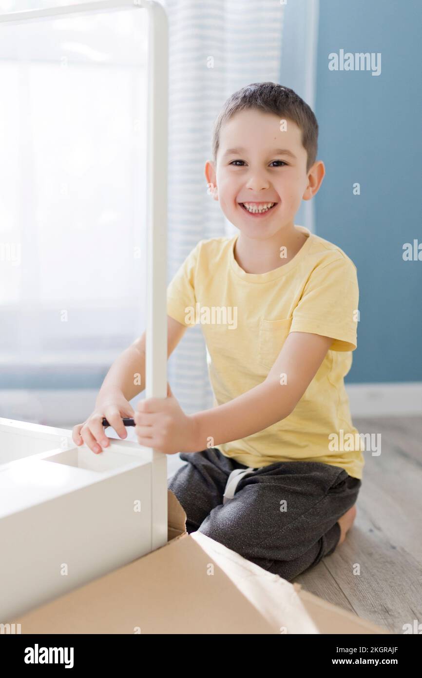Lächelnder Junge kniet zu Hause am Tisch Stockfoto
