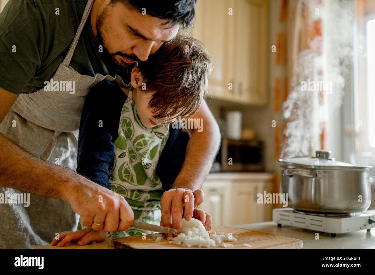 Vater brachte dem Sohn bei, Zwiebeln in der Küche zu hacken Stockfoto
