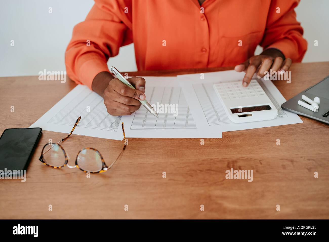 Eine Geschäftsfrau, die am Schreibtisch die Rechnung kalkuliert Stockfoto