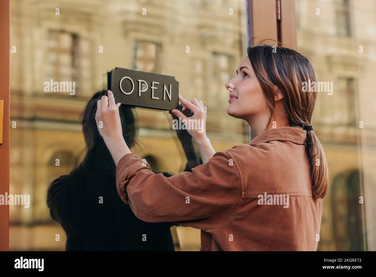 Jungunternehmer mit offenem Schild an der Glastür im Café Stockfoto