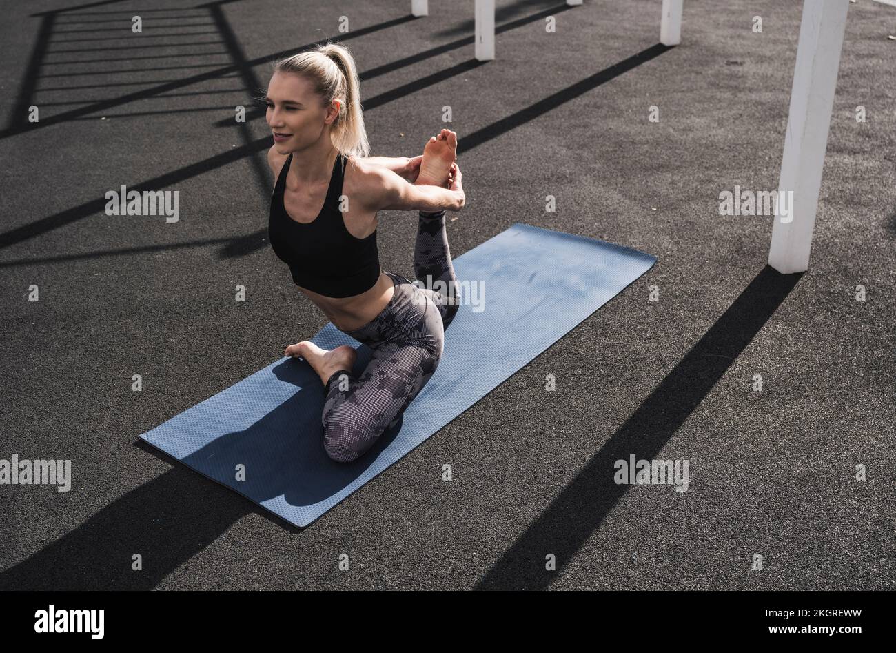 Lächelnde Sportlerin, die Yoga auf der Matte übt Stockfoto