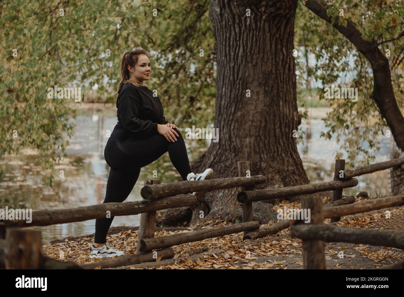 Übergroße Frau, die im Herbstpark trainiert Stockfoto