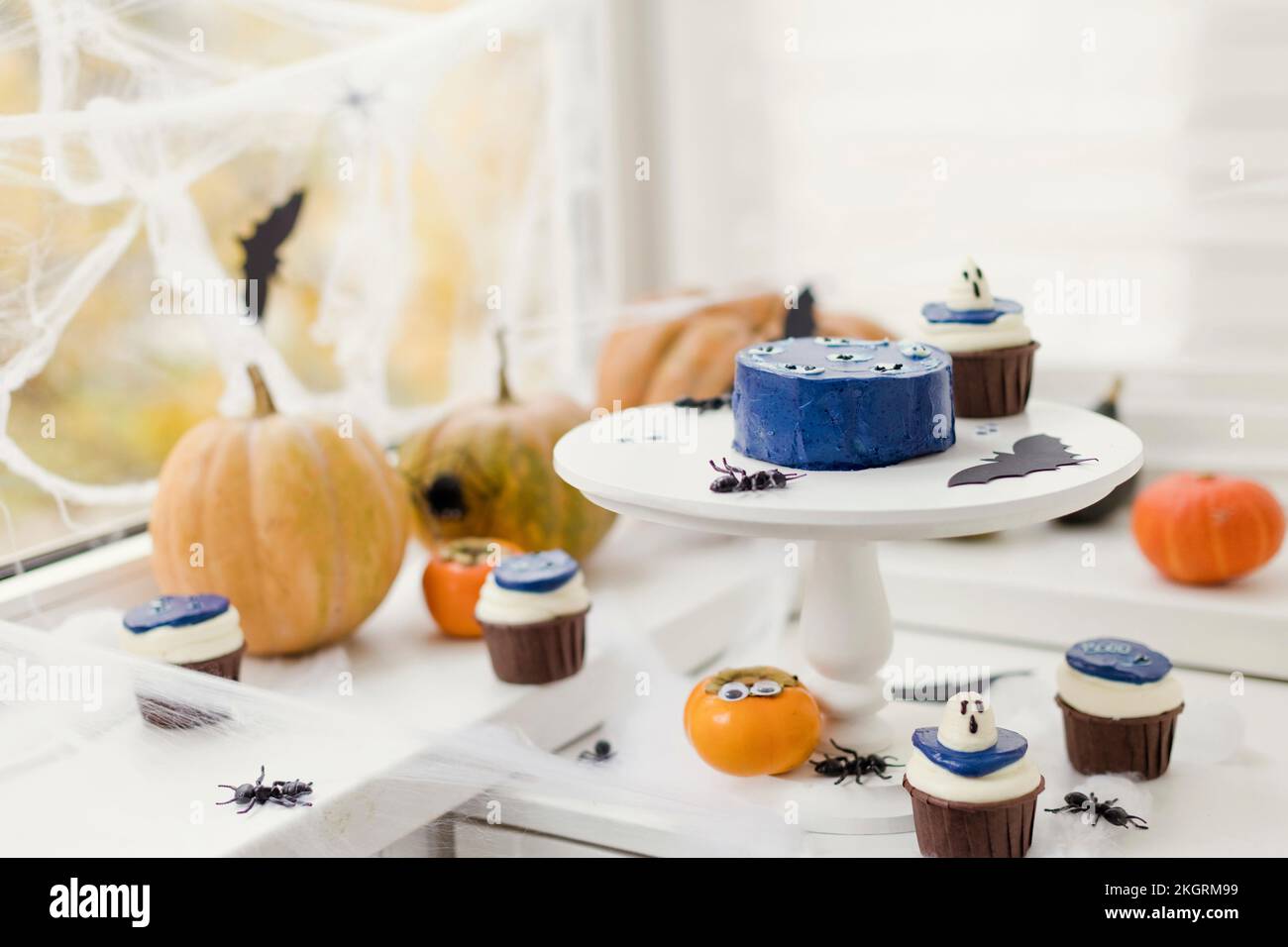 Kürbisse mit Cupcakes und Halloween-Dekoration auf dem Tisch zu Hause Stockfoto