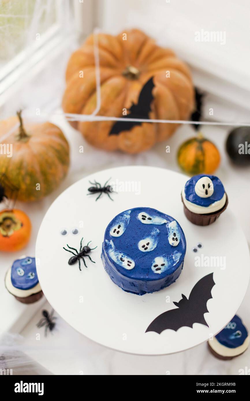 Kürbisse mit Kuchen und Halloween-Dekoration auf dem Tisch zu Hause Stockfoto