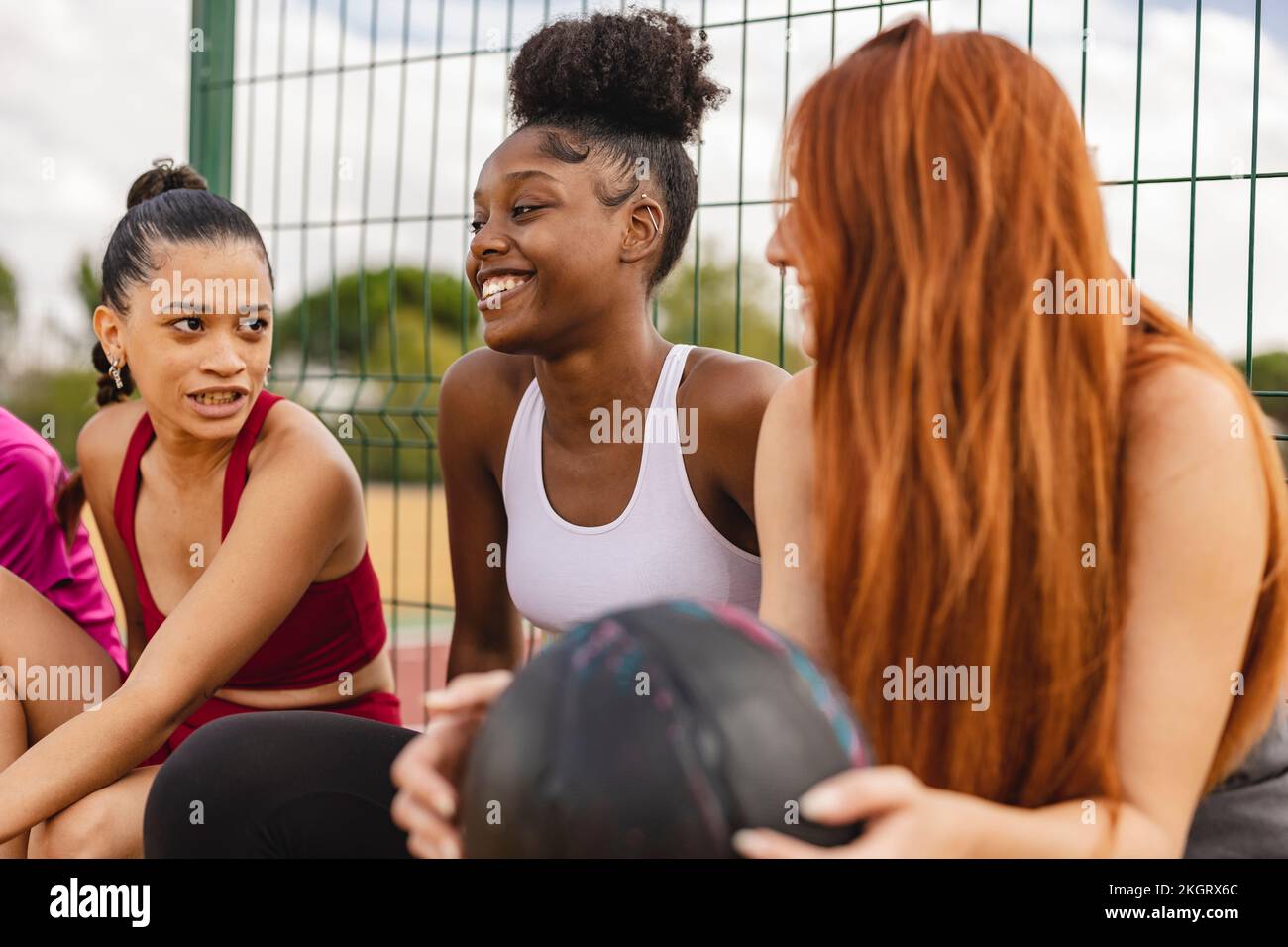 Glückliche Freunde, die Spaß haben, auf dem Sportplatz zu sitzen Stockfoto