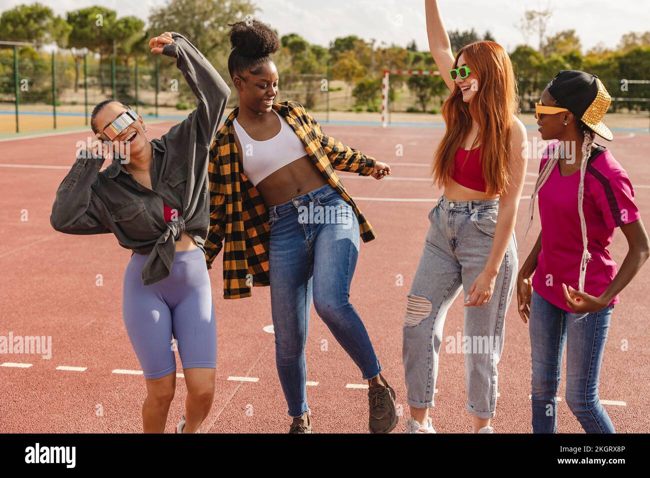 Fröhliche junge Freunde, die tanzen und Spaß auf dem Sportplatz haben Stockfoto