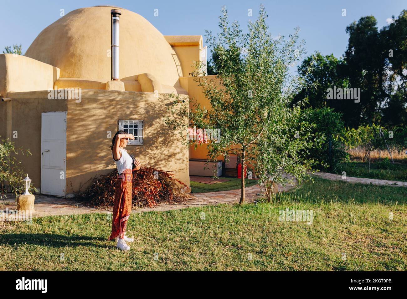 Eine Frau, die die Augen im Garten vor der geodätischen Kuppel schützt Stockfoto