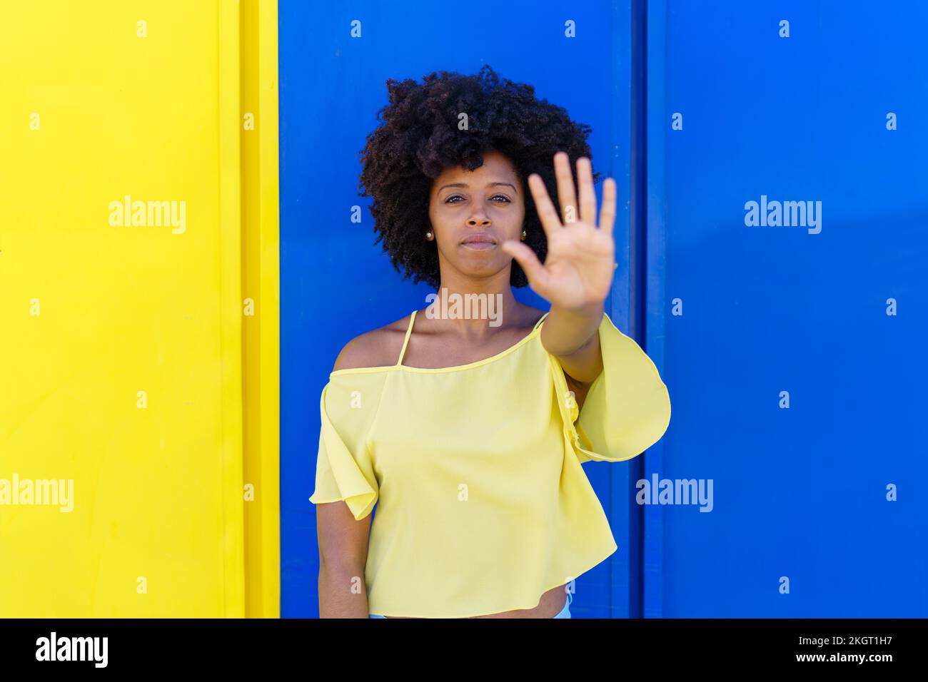 Frau mit Stoppgeste vor einer zweifarbigen Wand Stockfoto
