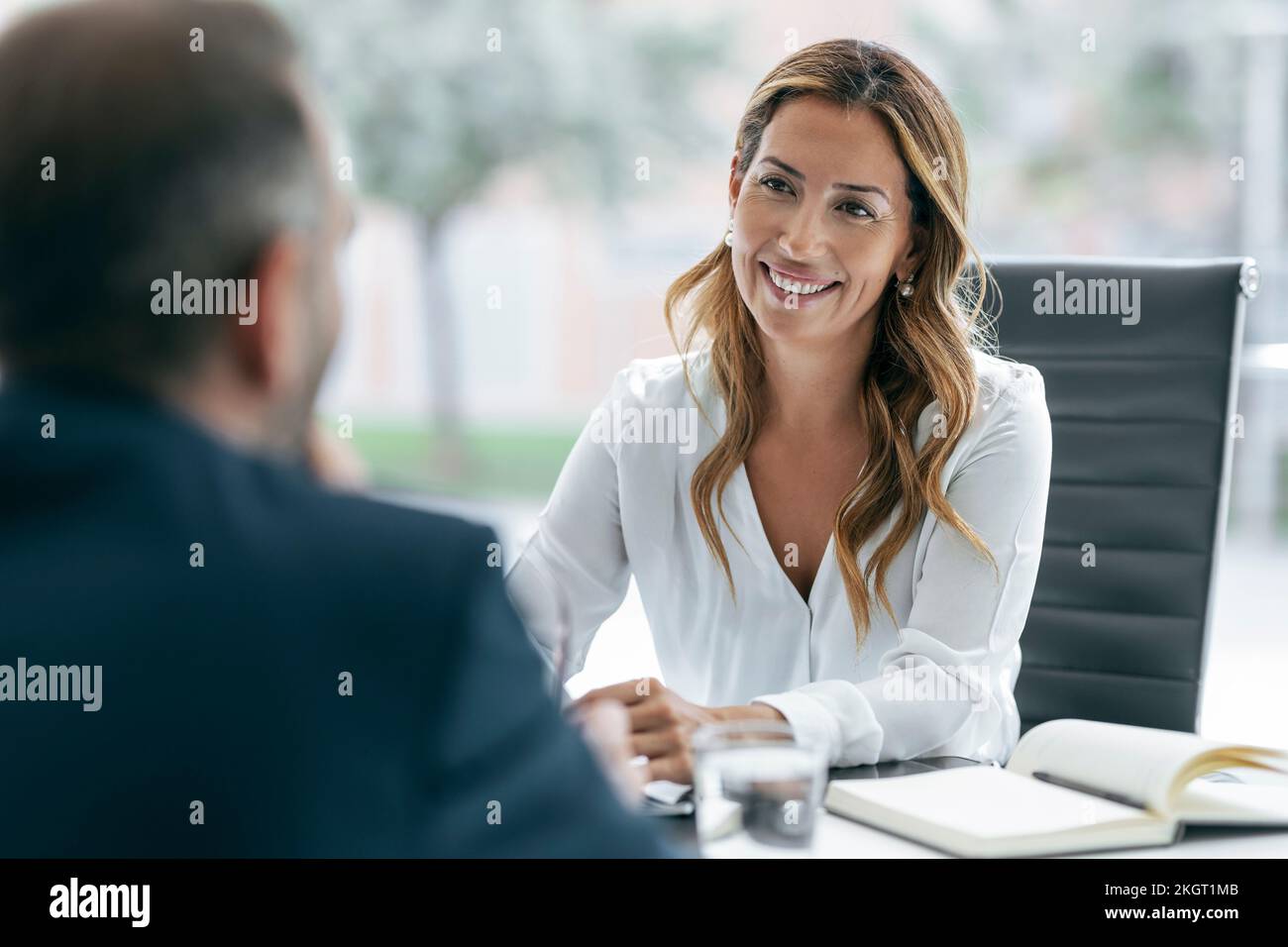 Glückliche Geschäftsfrau mit einem Kollegen, der im Meeting diskutiert Stockfoto