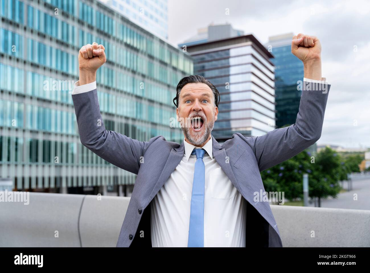 Fröhlicher Geschäftsmann, der vor dem Gebäude Fäuste zeigt Stockfoto
