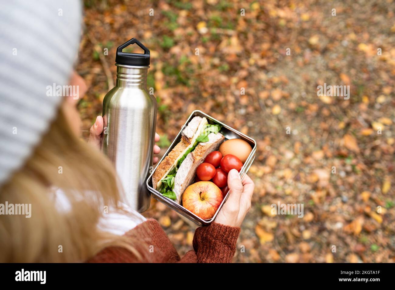 Frau mit Essensbox und Edelstahlflasche am Wochenende Stockfoto