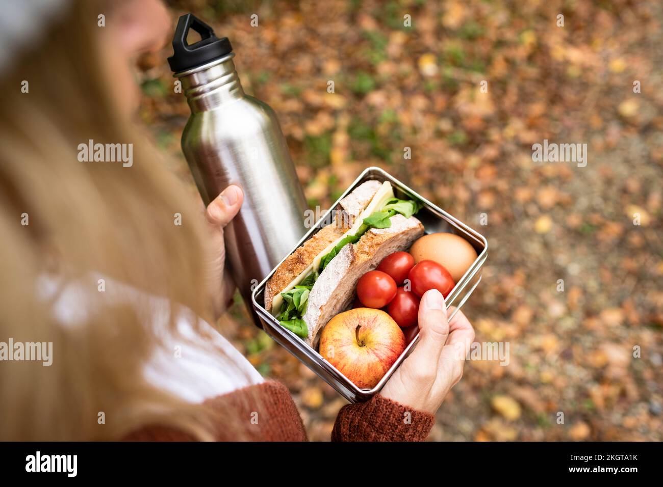 Frauenhand mit Essensbox und Wasserflasche Stockfoto