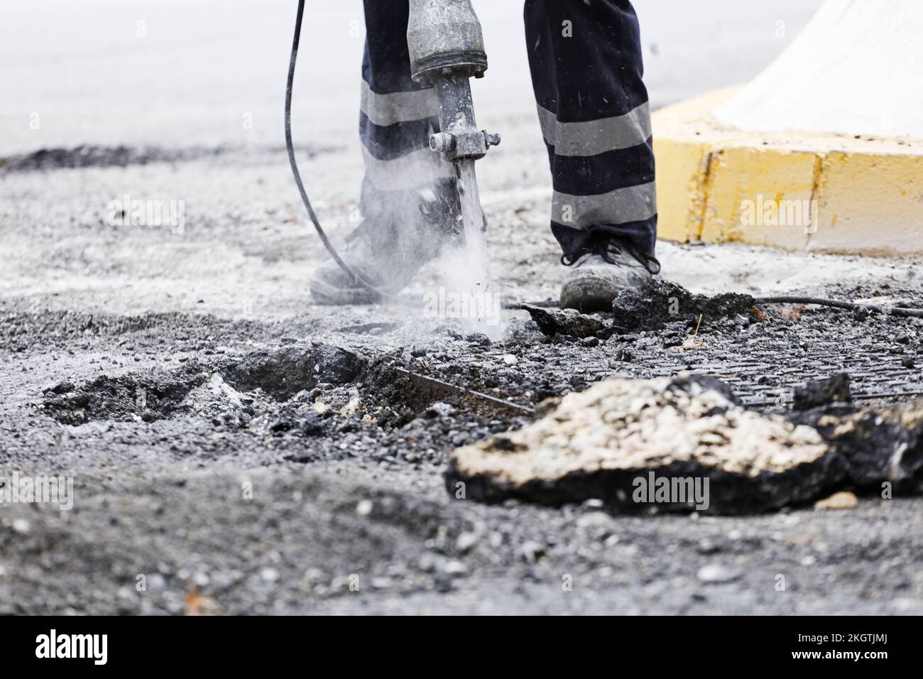 Der Bediener bohrt mit dem Hammer den Untergrund, um den neuen Asphalt zu montieren Stockfoto