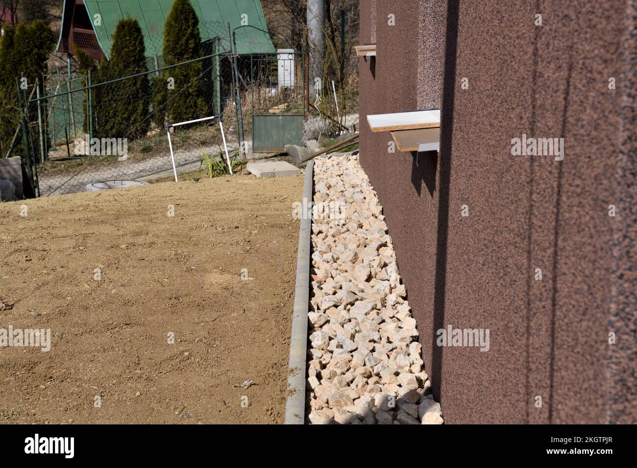 Ein Abflussweg aus dekorativen Steinen um die Wand des Hauses Stockfoto
